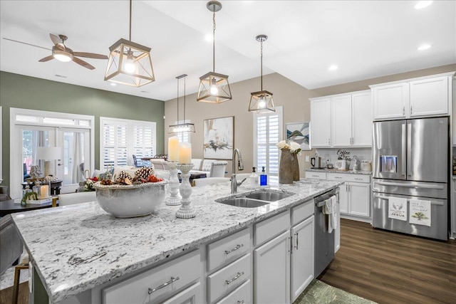 kitchen featuring stainless steel appliances, a sink, open floor plan, a ceiling fan, and a center island with sink