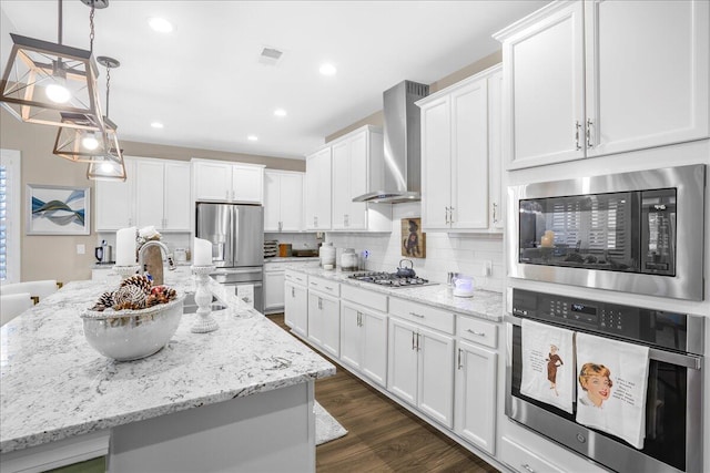 kitchen with stainless steel appliances, wall chimney exhaust hood, backsplash, white cabinetry, and dark wood-style flooring