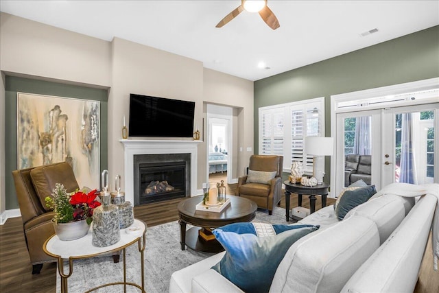 living area with wood finished floors, ceiling fan, a glass covered fireplace, and baseboards