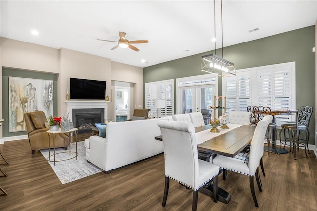 dining space featuring ceiling fan, a glass covered fireplace, dark wood-style floors, and recessed lighting