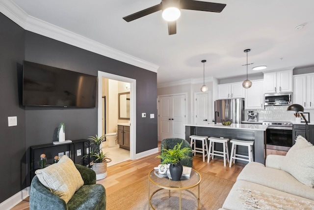 living room with ceiling fan, ornamental molding, and light hardwood / wood-style floors