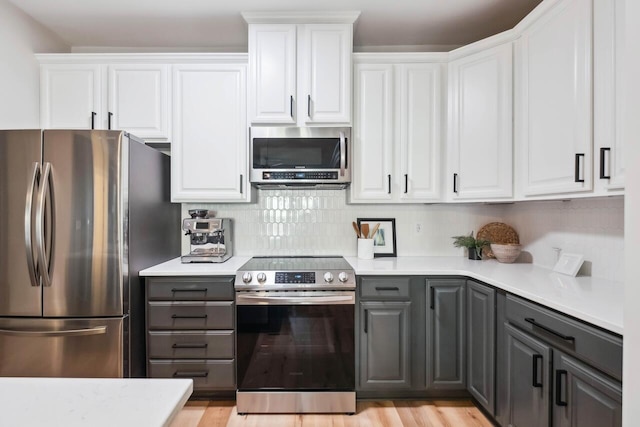 kitchen featuring gray cabinetry, stainless steel appliances, tasteful backsplash, and white cabinets