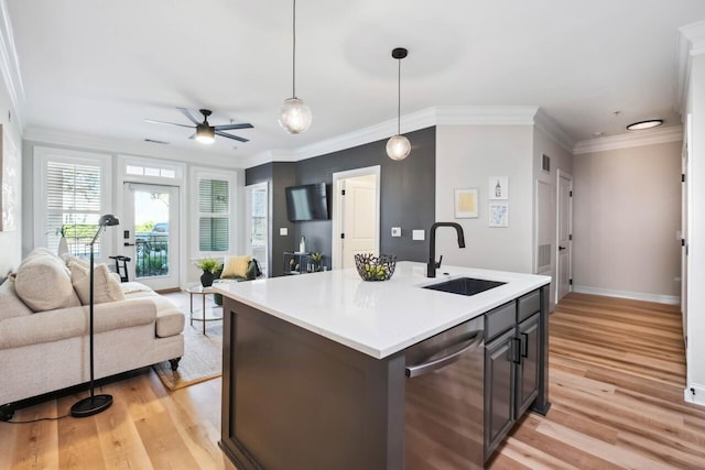 kitchen with sink, hanging light fixtures, an island with sink, stainless steel dishwasher, and light wood-type flooring