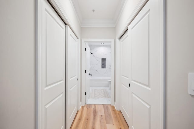 corridor with light hardwood / wood-style flooring and ornamental molding