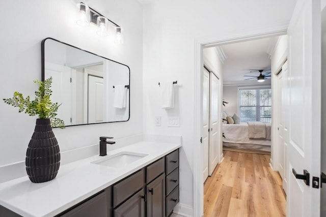 bathroom with vanity, wood-type flooring, ornamental molding, and ceiling fan