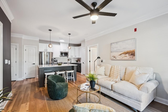 living room featuring ornamental molding, wood-type flooring, and ceiling fan