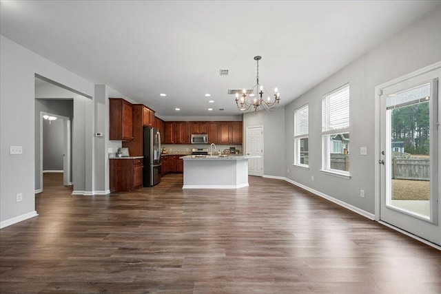 kitchen featuring sink, hanging light fixtures, stainless steel appliances, a center island with sink, and an inviting chandelier