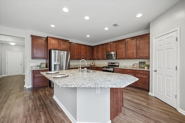 kitchen featuring appliances with stainless steel finishes, a kitchen island with sink, sink, and dark wood-type flooring