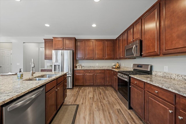 kitchen featuring stainless steel appliances, light stone countertops, sink, and light hardwood / wood-style floors