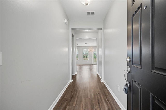 hall featuring dark hardwood / wood-style flooring and an inviting chandelier