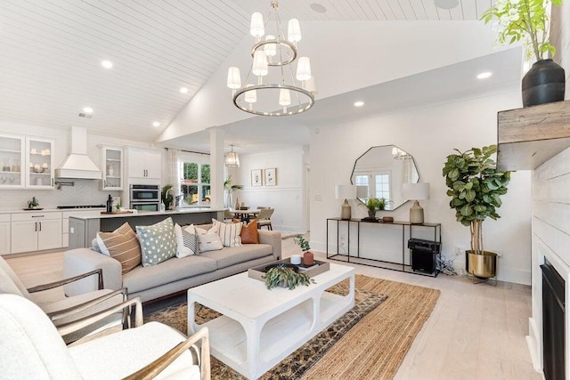 living room with wooden ceiling, light hardwood / wood-style flooring, high vaulted ceiling, and an inviting chandelier