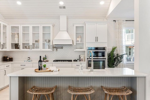 kitchen featuring a kitchen breakfast bar, double oven, and custom exhaust hood