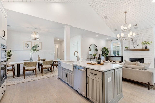 kitchen with pendant lighting, a center island with sink, gray cabinets, a fireplace, and appliances with stainless steel finishes