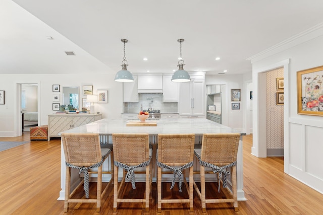 kitchen with a spacious island, pendant lighting, a breakfast bar, and white cabinetry