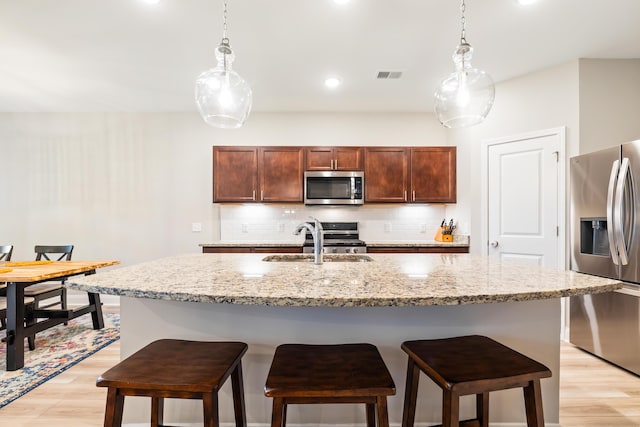 3010 Grinnell St, Johns Island, SC 29455 - kitchen featuring stainless steel appliances, a sink, light wood-type flooring, tasteful backsplash, and a kitchen breakfast bar