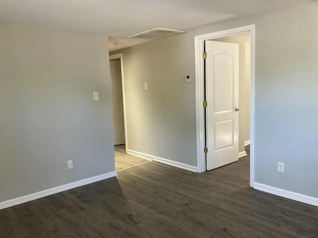 spare room with baseboards, visible vents, and dark wood-style flooring