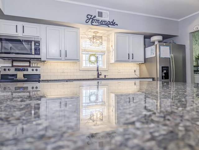 49 Auld Brass Rd, Walterboro, SC 29488 - kitchen with appliances with stainless steel finishes, ornamental molding, decorative backsplash, dark stone counters, and white cabinetry