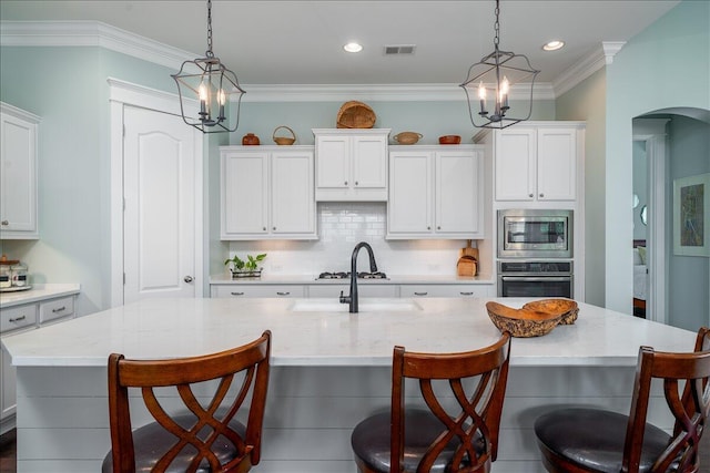 kitchen featuring oven, a notable chandelier, a sink, stainless steel microwave, and backsplash