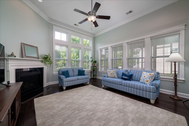 living room featuring visible vents, baseboards, wood finished floors, and crown molding