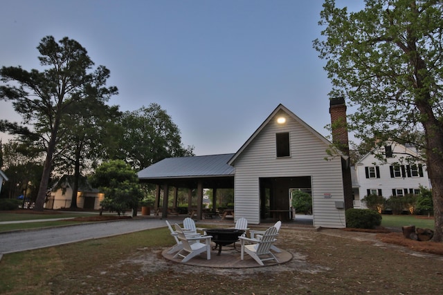rear view of property with a fire pit, a chimney, and a patio