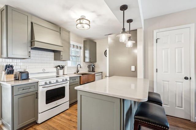 kitchen with a kitchen bar, premium range hood, white appliances, gray cabinets, and hanging light fixtures