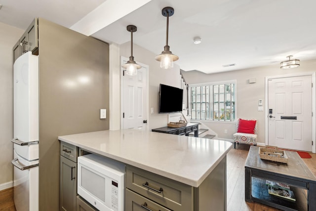 kitchen with gray cabinetry, dark hardwood / wood-style floors, white appliances, and hanging light fixtures