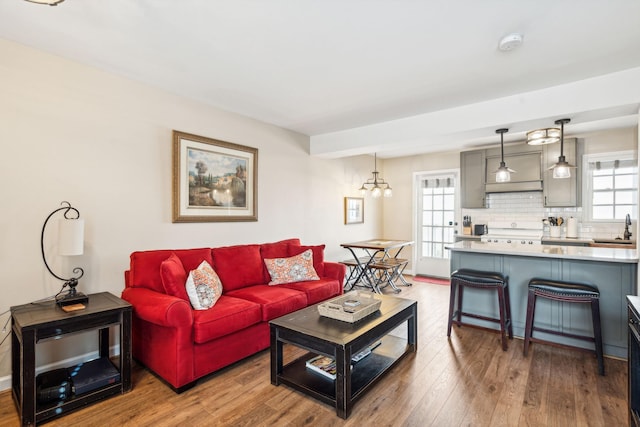 living room featuring hardwood / wood-style floors, an inviting chandelier, and sink