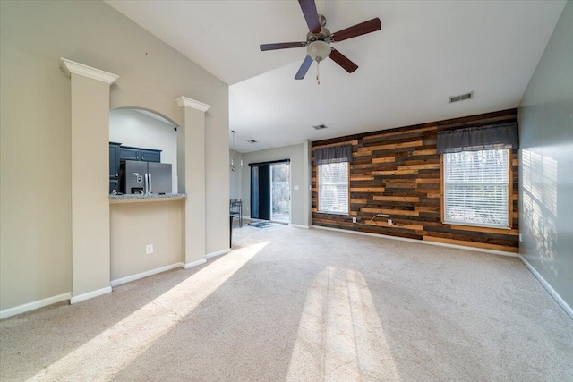 unfurnished living room with ceiling fan, carpet floors, and wooden walls