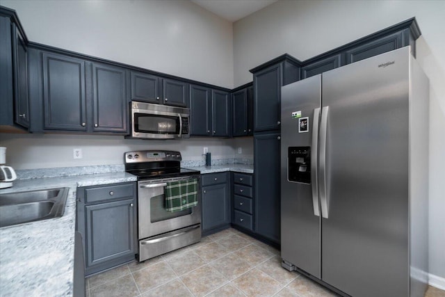 kitchen with light stone counters, stainless steel appliances, sink, and light tile patterned floors