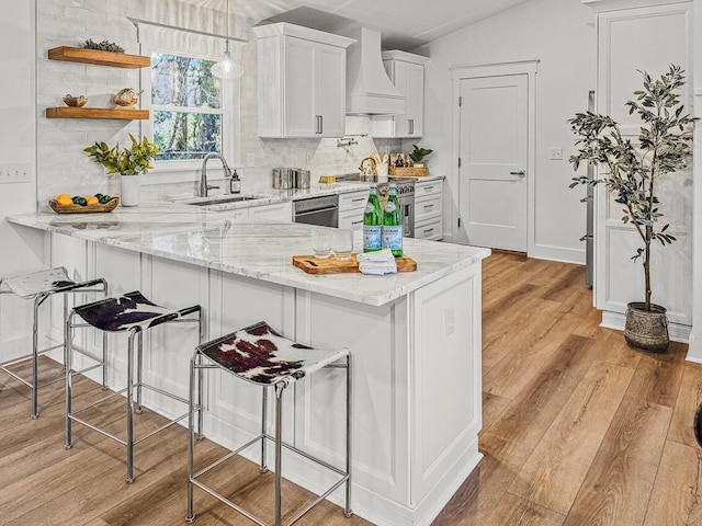 kitchen with stainless steel appliances, white cabinetry, custom range hood, and kitchen peninsula