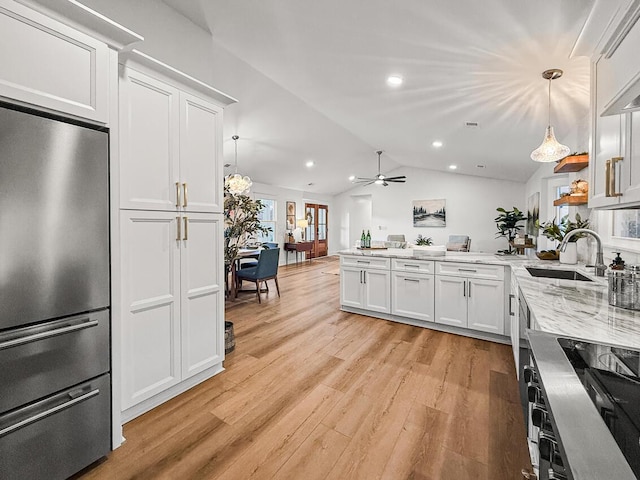 kitchen with sink, white cabinets, decorative light fixtures, vaulted ceiling, and built in fridge