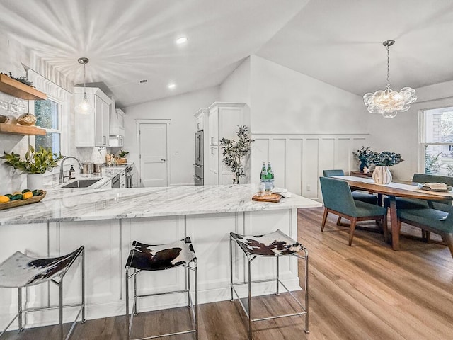 kitchen featuring pendant lighting, sink, stainless steel range oven, white cabinets, and kitchen peninsula