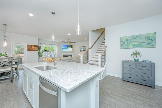 kitchen featuring dishwasher, sink, decorative light fixtures, white cabinets, and light wood-type flooring