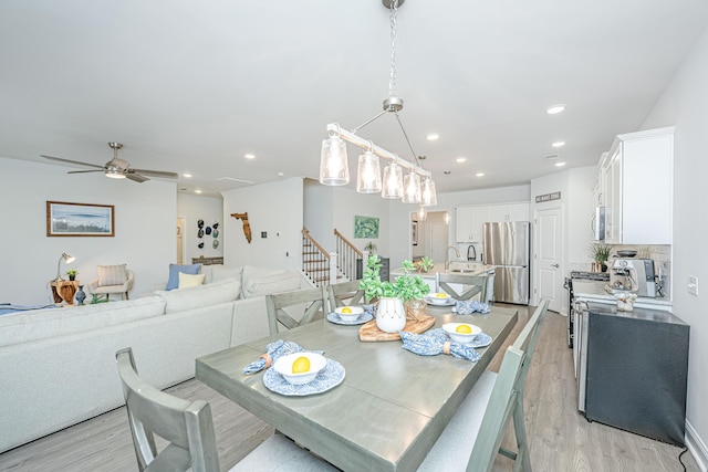 dining space featuring ceiling fan, light wood-type flooring, and sink