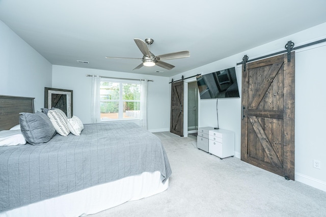 bedroom with light carpet, a barn door, and ceiling fan