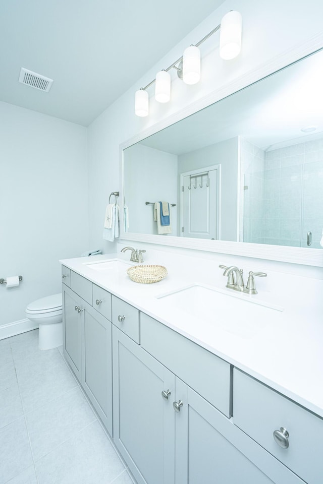 bathroom featuring tiled shower, tile patterned floors, vanity, and toilet