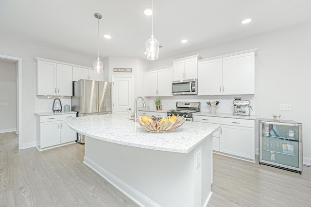 kitchen featuring white cabinets, light hardwood / wood-style floors, beverage cooler, and appliances with stainless steel finishes