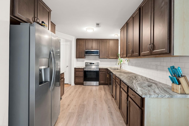 kitchen with light wood-type flooring, stainless steel appliances, dark brown cabinetry, and sink