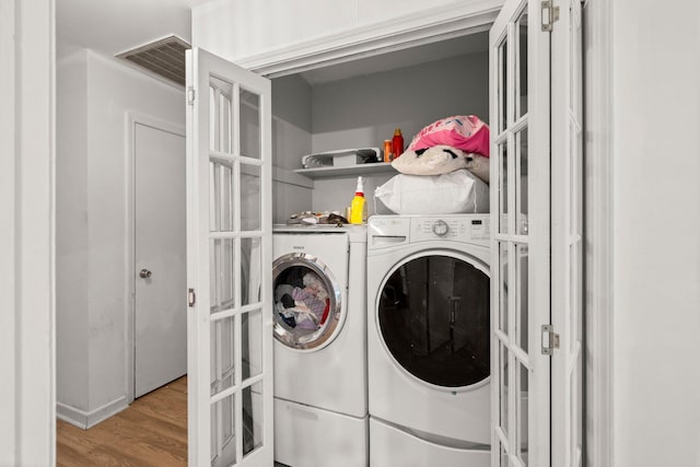 washroom featuring washer and dryer, french doors, and light hardwood / wood-style floors