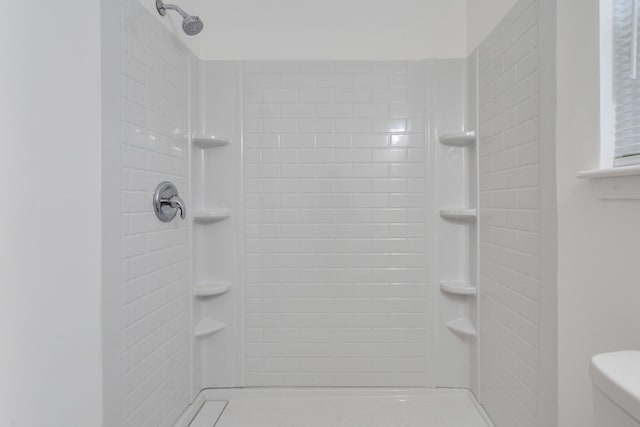 bathroom with a tile shower and toilet