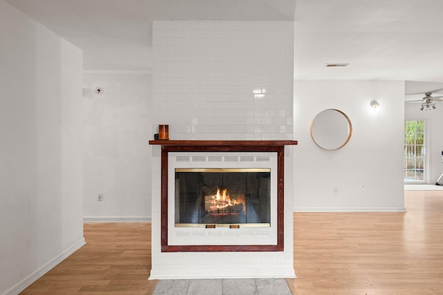 unfurnished living room featuring a fireplace, light hardwood / wood-style floors, and ceiling fan