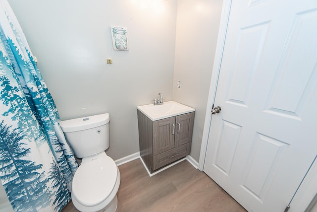 bathroom featuring hardwood / wood-style floors, curtained shower, vanity, and toilet