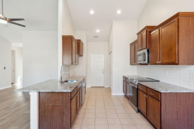 kitchen featuring ceiling fan, sink, stainless steel appliances, light stone counters, and light tile patterned floors