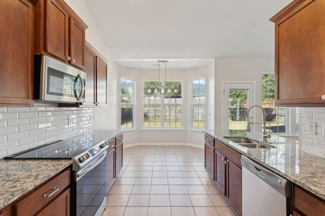 kitchen featuring sink, light stone counters, pendant lighting, light tile patterned floors, and appliances with stainless steel finishes