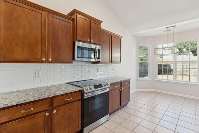 kitchen with decorative light fixtures, light stone counters, light tile patterned floors, and appliances with stainless steel finishes