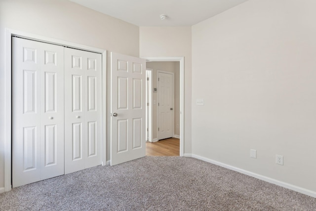 unfurnished bedroom with light colored carpet and a closet