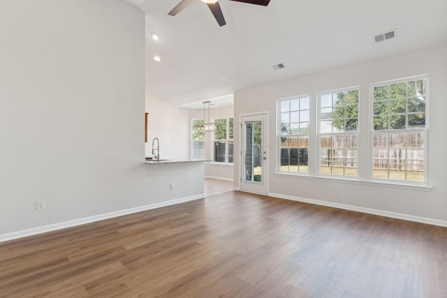 unfurnished living room featuring ceiling fan, hardwood / wood-style floors, lofted ceiling, and sink