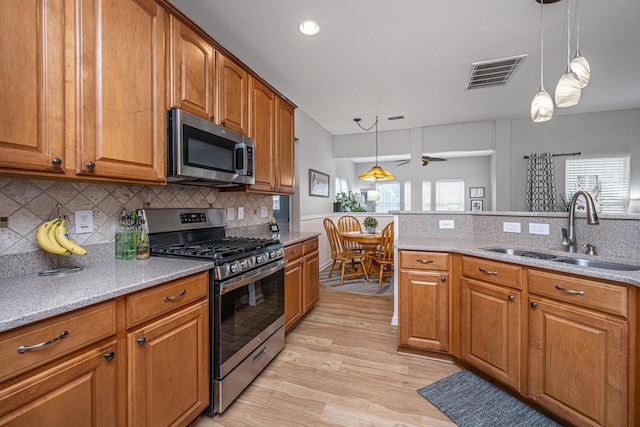 9636 Pebble Creek Blvd, Summerville, SC 29485 - kitchen with appliances with stainless steel finishes, a sink, brown cabinets, tasteful backsplash, and pendant lighting