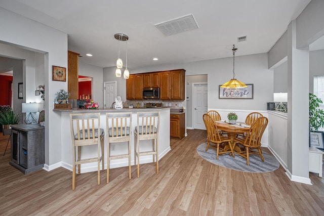 9636 Pebble Creek Blvd, Summerville, SC 29485 - kitchen featuring stainless steel microwave, brown cabinets, light wood-type flooring, hanging light fixtures, and recessed lighting