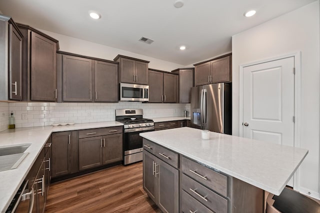 kitchen featuring tasteful backsplash, dark brown cabinets, dark hardwood / wood-style floors, and appliances with stainless steel finishes